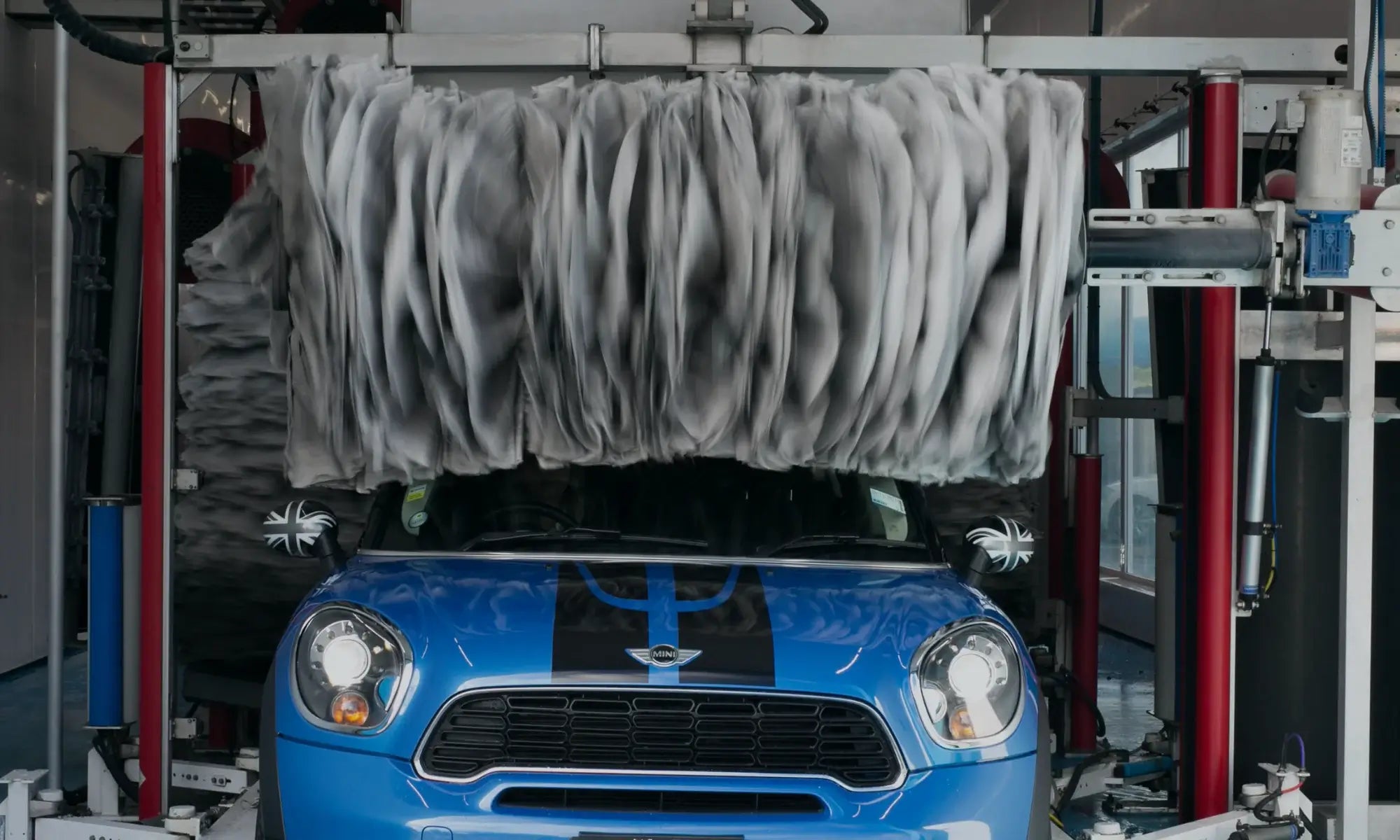 Blue Mini Cooper inside automated tunnel wash system